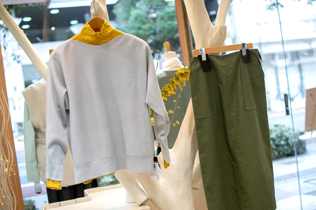 ミモザカラーのレイヤードコーデ。グレーのホールガーメントニットとイエローのインナー、カーキタイトスカートの春スタイル。