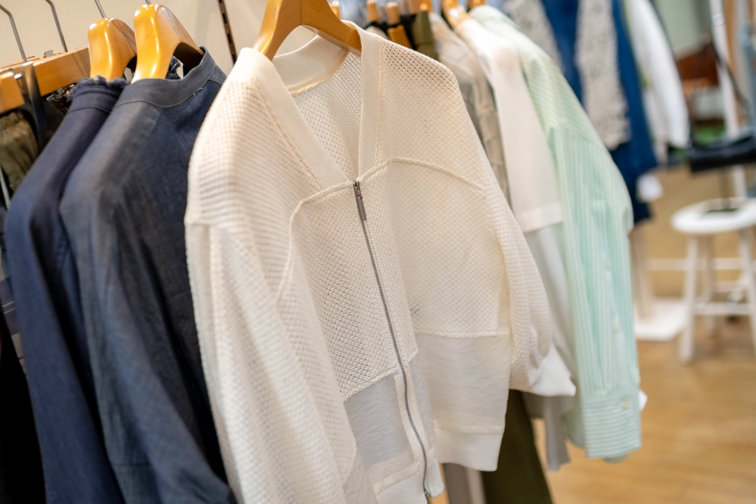 ハンガーに掛かった白のメッシュで裾がシアーのブルゾン。正面のジッパーが見える角度